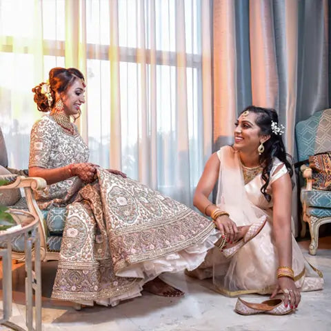 Priya Patel, New Jersey, in a silver embroidered lehenga with a bridesmaid adjusting her jutti