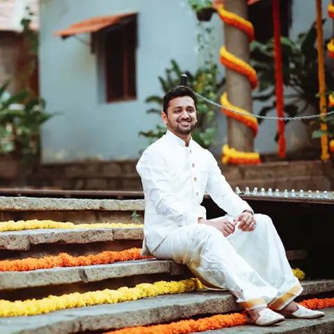 Sandeep Gangundi, San Francisco, in a white kurta and pyjama on steps decorated with marigold garlands