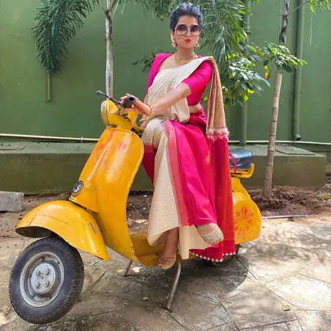 Surabhi Prahalad, San Jose, in a pink and cream saree and sunglasses on a yellow vintage scooter