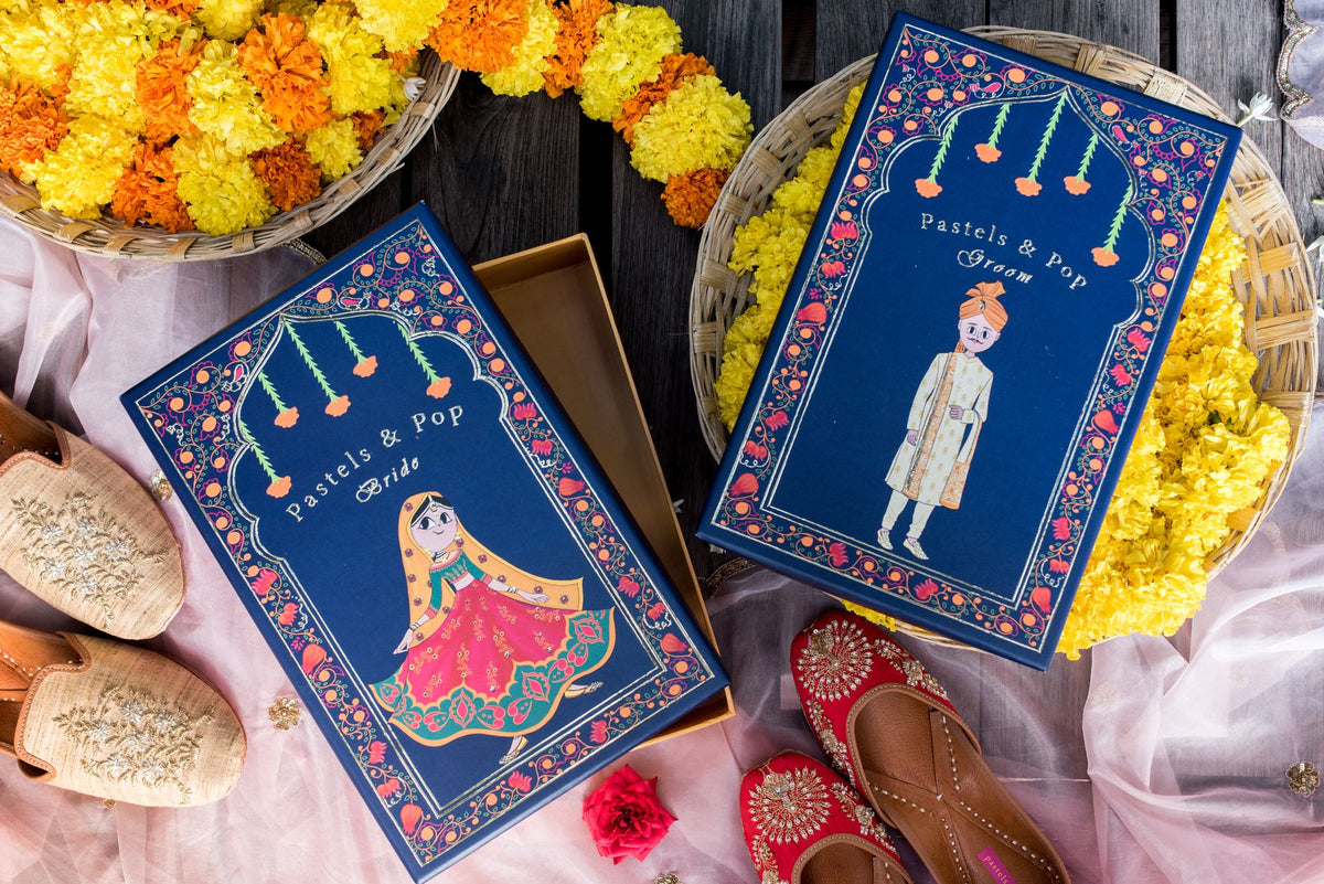 Handcrafted for your big day, the Pastels & Pop Wedding Box in navy with bride and groom illustrations, surrounded by marigolds