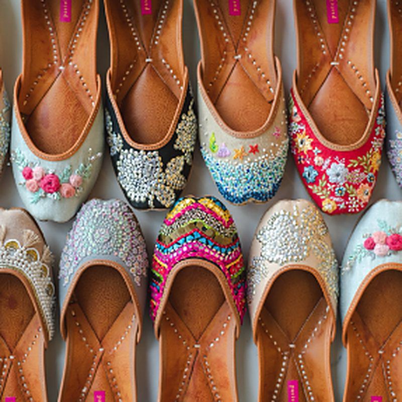 Rows of handcrafted Pastels & Pop juttis in pastel, black and red, covered in embroidery, beads and sequins
